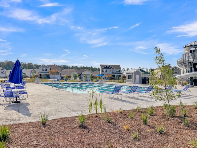 pool with an outbuilding, a patio, fence, a residential view, and a shed