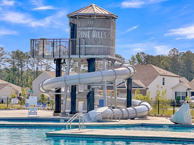 community pool with a water slide and fence