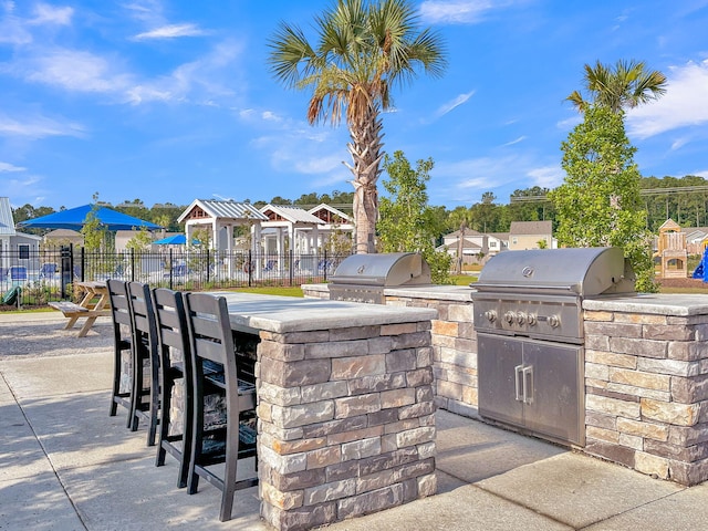 view of patio / terrace featuring outdoor dry bar, area for grilling, a grill, and fence