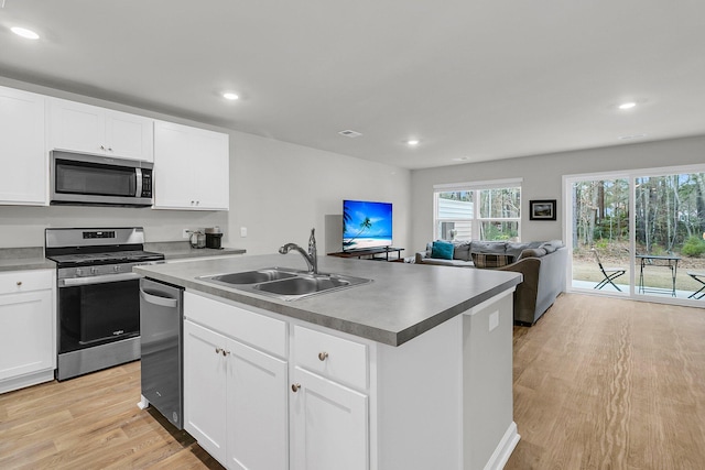 kitchen with stainless steel appliances, light wood-type flooring, white cabinetry, and a sink