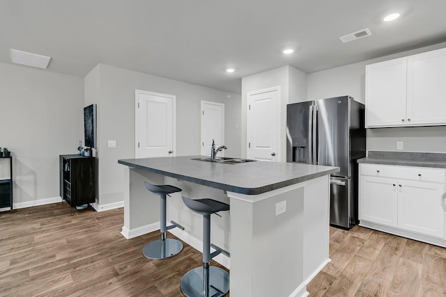 kitchen with dark countertops, stainless steel refrigerator with ice dispenser, a sink, and visible vents