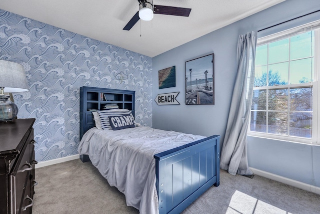 carpeted bedroom with wallpapered walls, baseboards, and a ceiling fan