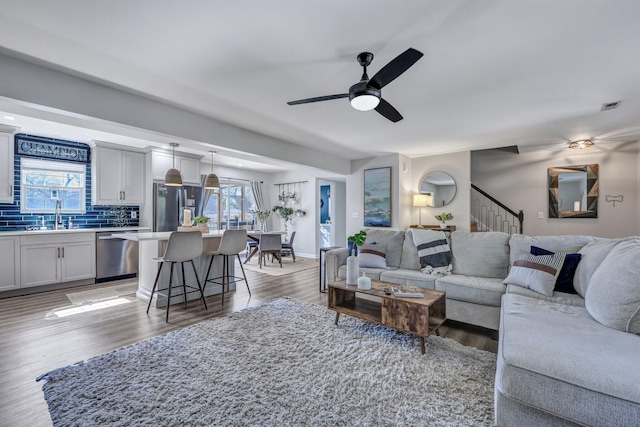 living area featuring visible vents, plenty of natural light, a ceiling fan, and light wood finished floors