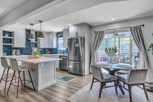 kitchen with light wood-type flooring, gray cabinets, backsplash, stainless steel appliances, and light countertops