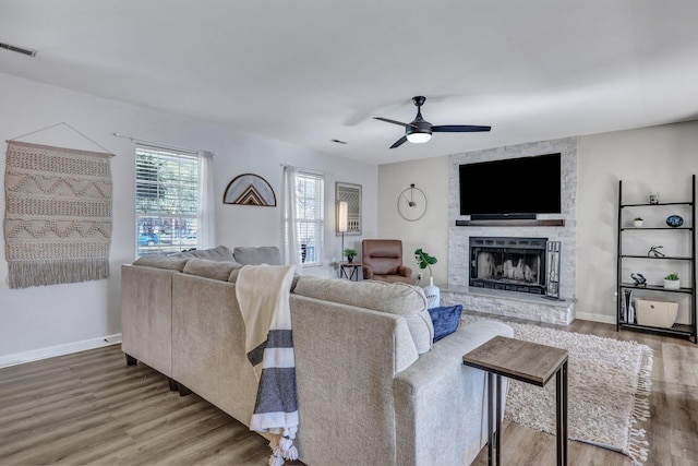 living area with visible vents, a fireplace, baseboards, and wood finished floors