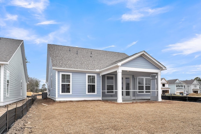 rear view of property with a lawn, central AC unit, and a sunroom