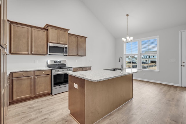 kitchen with appliances with stainless steel finishes, light hardwood / wood-style flooring, a center island with sink, decorative light fixtures, and sink