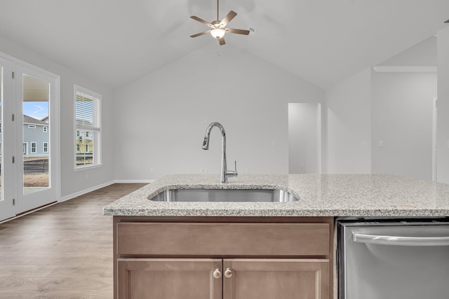 kitchen featuring dishwasher, light wood-type flooring, light stone countertops, vaulted ceiling, and sink