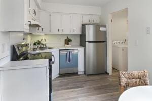 519 Parkdale Dr Unit J, Charleston, SC 29414 - kitchen with appliances with stainless steel finishes, wood finished floors, a sink, light countertops, and under cabinet range hood