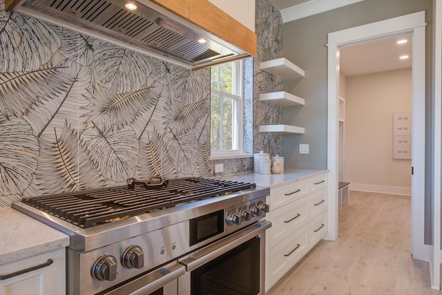 kitchen with backsplash, light wood-type flooring, white cabinetry, custom range hood, and stainless steel range