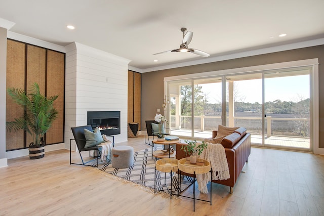 living room with a large fireplace, light wood-type flooring, and ceiling fan