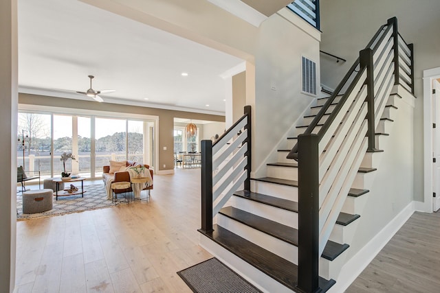 stairway with hardwood / wood-style floors, ceiling fan, and ornamental molding