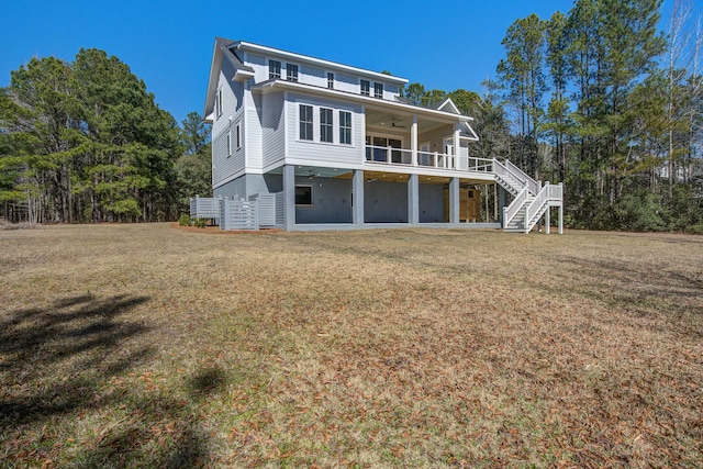 rear view of house with ceiling fan, a deck, and a lawn