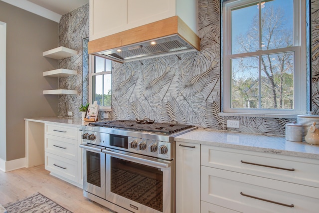 kitchen featuring white cabinets, premium range hood, high end stainless steel range oven, and light stone counters