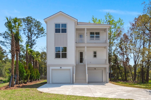 coastal home with a garage, a balcony, concrete driveway, and stairway