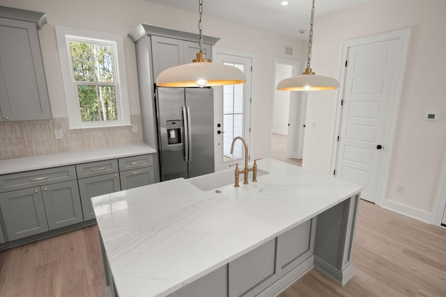 kitchen with light wood-style flooring, a sink, stainless steel refrigerator with ice dispenser, and gray cabinetry