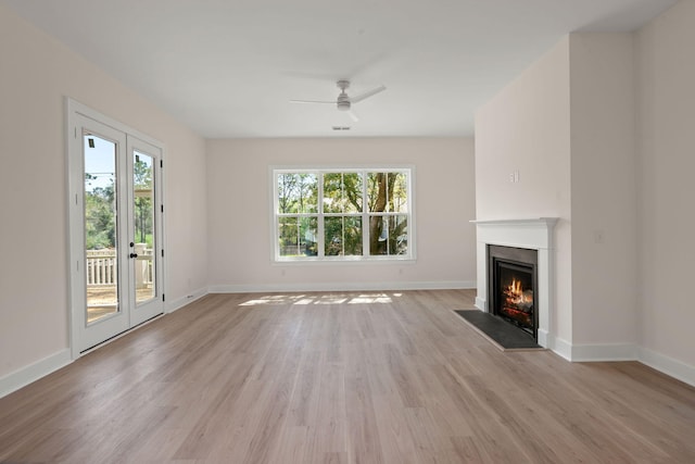 unfurnished living room featuring a fireplace with flush hearth, baseboards, light wood-type flooring, and a ceiling fan