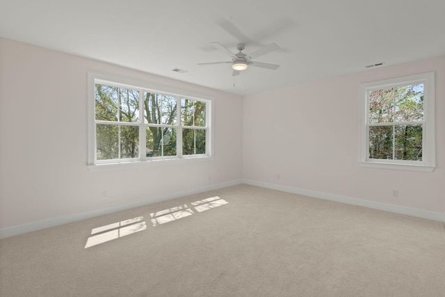 empty room featuring light colored carpet, visible vents, ceiling fan, and baseboards