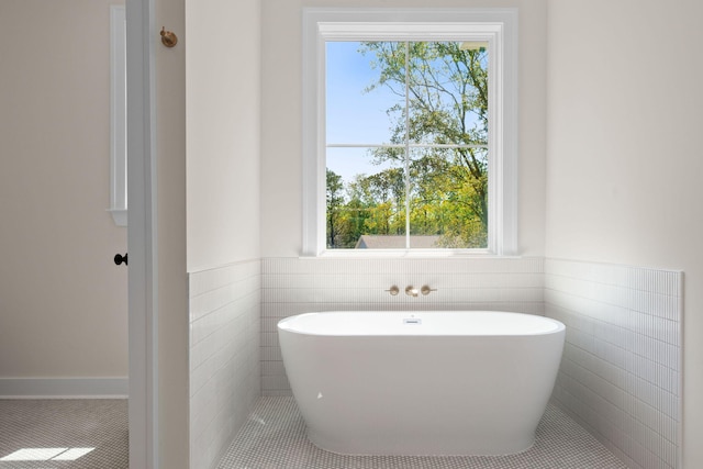 full bath with tile patterned flooring, a wainscoted wall, and a freestanding tub