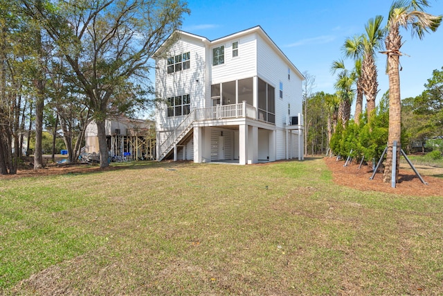 back of house featuring stairs, a sunroom, and a lawn