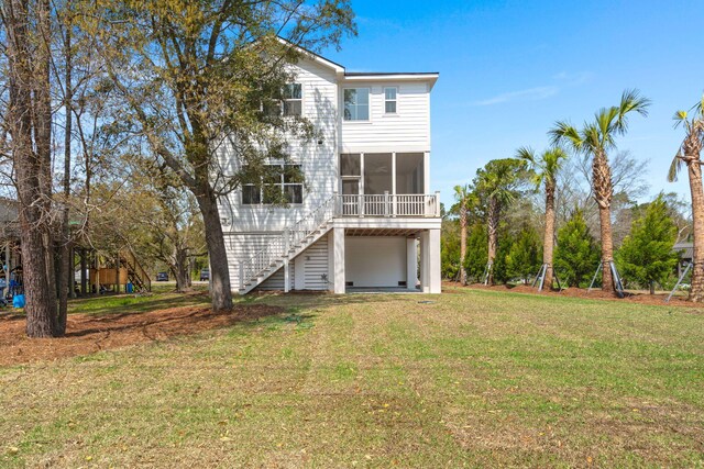 rear view of property with stairs, a sunroom, and a lawn