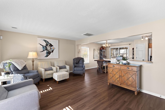 living room with dark wood-type flooring, a notable chandelier, and a textured ceiling