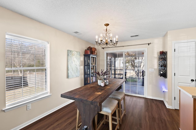 dining room with a chandelier, a textured ceiling, and dark hardwood / wood-style flooring