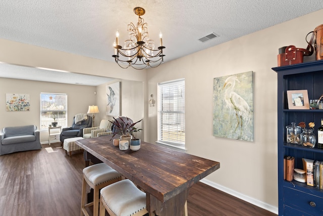 dining area featuring dark hardwood / wood-style flooring, a notable chandelier, a wealth of natural light, and a textured ceiling