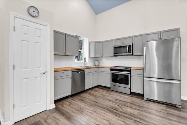 5233 Maybank Hwy, Wadmalaw Island, SC 29487 - kitchen with stainless steel appliances, butcher block counters, gray cabinets, wood finished floors, and a towering ceiling