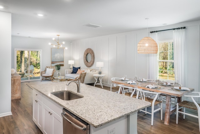 kitchen featuring dishwasher, open floor plan, hanging light fixtures, white cabinetry, and a sink