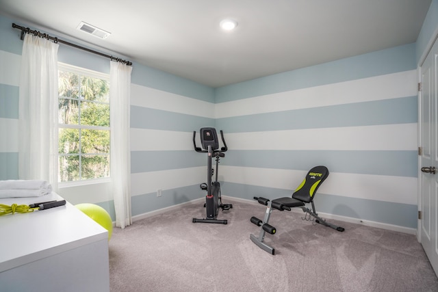 exercise room with visible vents, light carpet, and baseboards