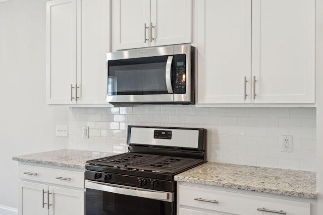 kitchen with light stone countertops, white cabinetry, stainless steel appliances, and decorative backsplash