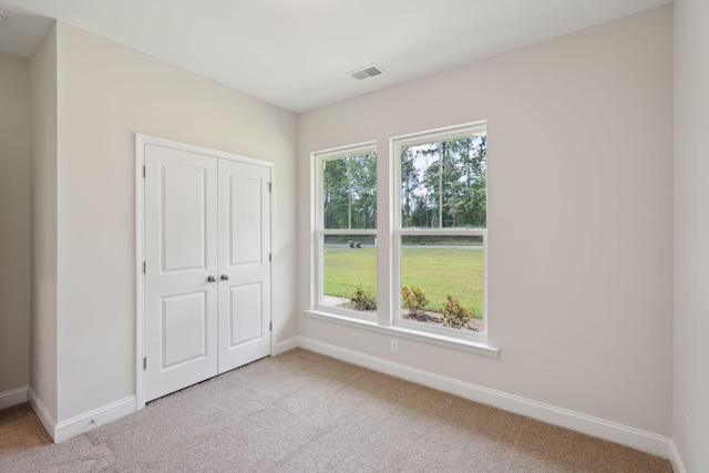 unfurnished bedroom with light carpet, baseboards, visible vents, and a closet