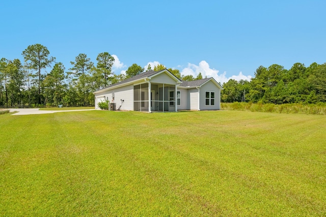 back of property featuring a garage, a yard, concrete driveway, and a sunroom