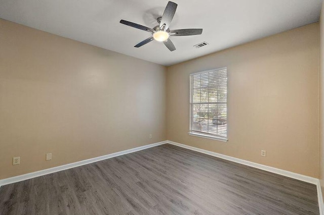 empty room featuring visible vents, baseboards, dark wood finished floors, and a ceiling fan