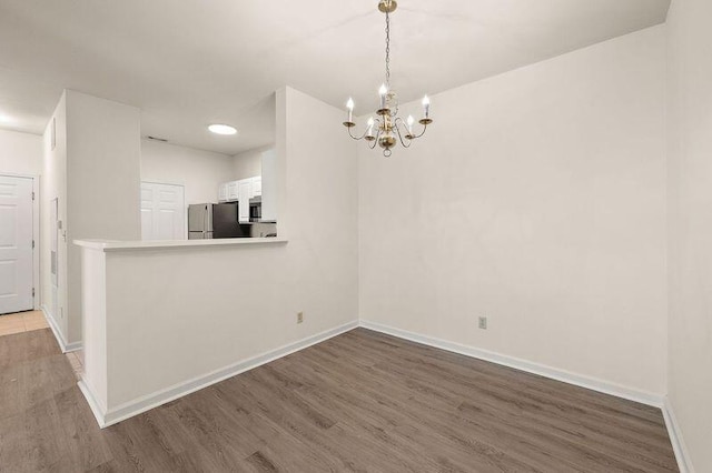 interior space with baseboards, a notable chandelier, and wood finished floors