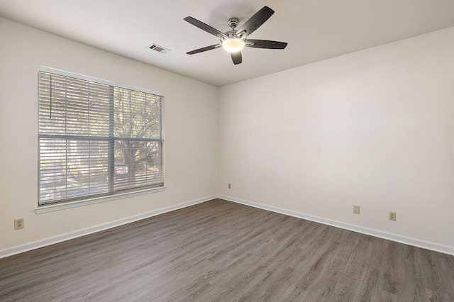 spare room featuring visible vents, baseboards, and dark wood-style floors