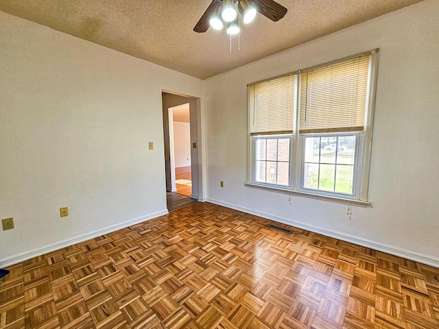 empty room featuring ceiling fan, baseboards, visible vents, and a textured ceiling