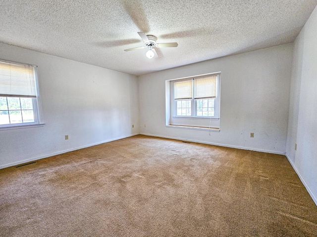 unfurnished room with visible vents, baseboards, carpet flooring, a textured ceiling, and a ceiling fan