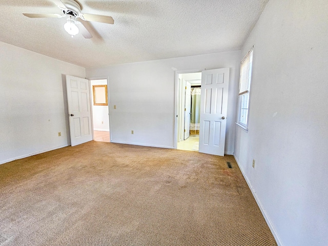 unfurnished bedroom with baseboards, visible vents, ensuite bathroom, a textured ceiling, and light colored carpet