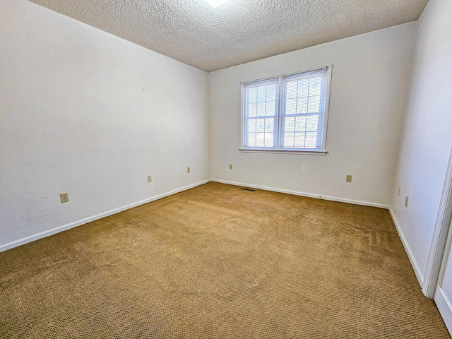 spare room with baseboards, carpet flooring, a textured ceiling, and visible vents