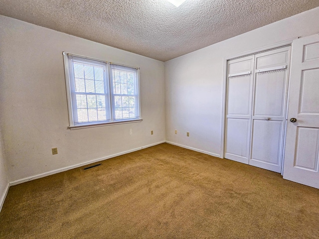 unfurnished bedroom featuring visible vents, baseboards, carpet floors, a closet, and a textured ceiling