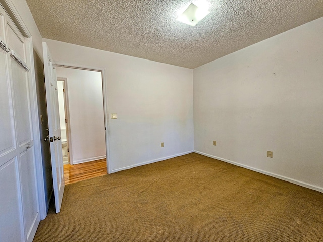 interior space with a textured ceiling, baseboards, and carpet