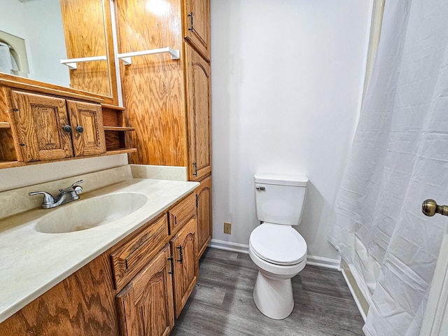 bathroom featuring baseboards, toilet, a shower with curtain, wood finished floors, and vanity