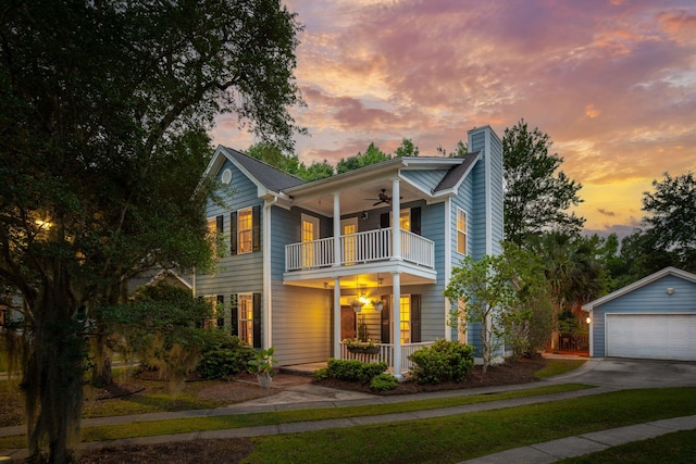 view of front facade with a balcony, ceiling fan, a chimney, a porch, and a garage