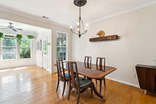 dining space featuring light wood-style flooring, a chandelier, ornamental molding, ceiling fan, and baseboards