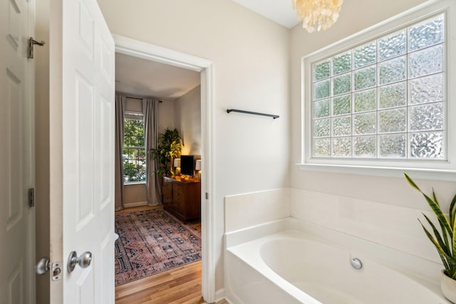 bathroom featuring a bath, wood finished floors, and a chandelier