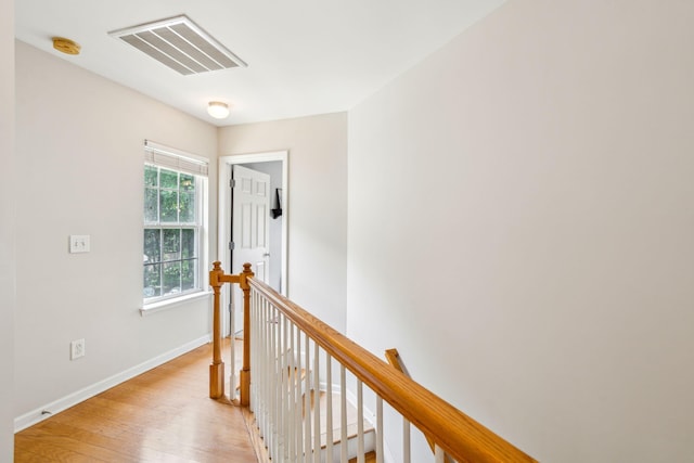 corridor with an upstairs landing, light wood-type flooring, and baseboards