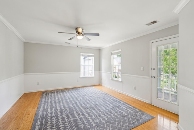 spare room featuring wood finished floors, ceiling fan, ornamental molding, and baseboards
