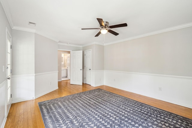 empty room featuring wood-type flooring, ceiling fan, crown molding, and baseboards